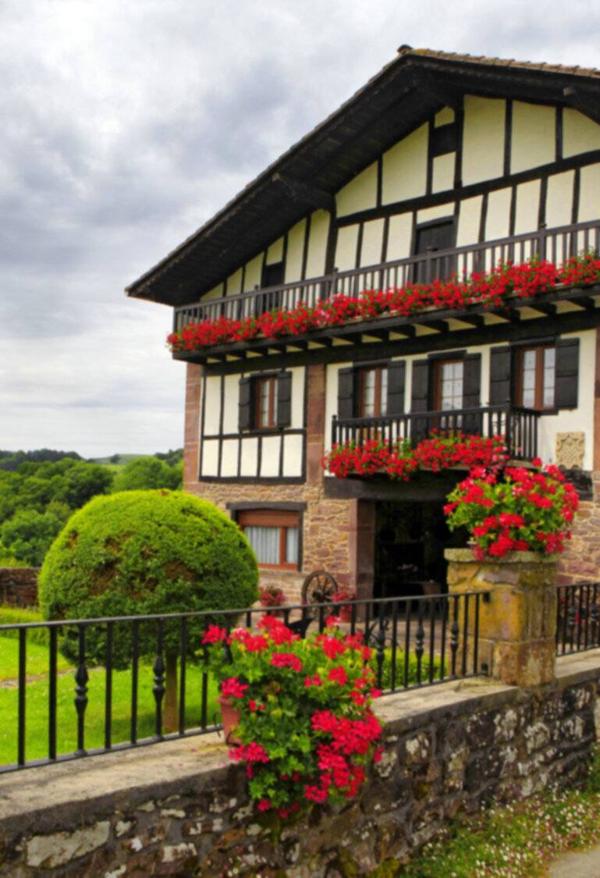 White house with wooden beams with red geraniums